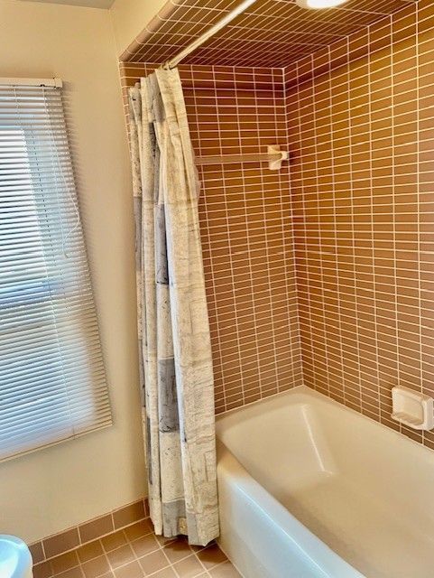 bathroom featuring tile patterned flooring, a wealth of natural light, and shower / tub combo with curtain