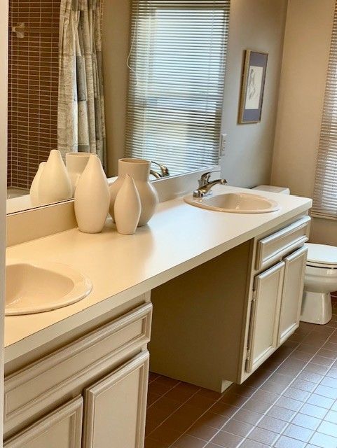 bathroom featuring a shower with shower curtain, double vanity, a sink, tile patterned floors, and toilet