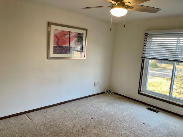 empty room featuring visible vents, baseboards, ceiling fan, and carpet flooring