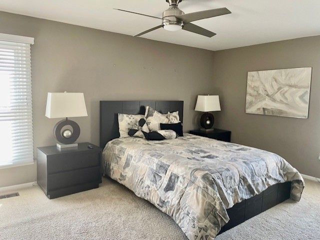 bedroom featuring multiple windows, light carpet, baseboards, and visible vents