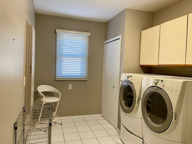 laundry room featuring light tile patterned floors, cabinet space, independent washer and dryer, and baseboards