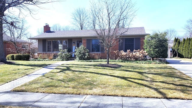 ranch-style house with a porch, brick siding, a chimney, and a front yard