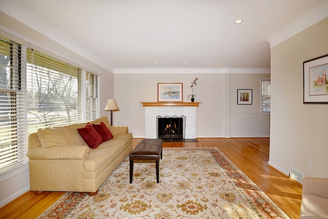 living room with visible vents, wood finished floors, recessed lighting, baseboards, and a brick fireplace