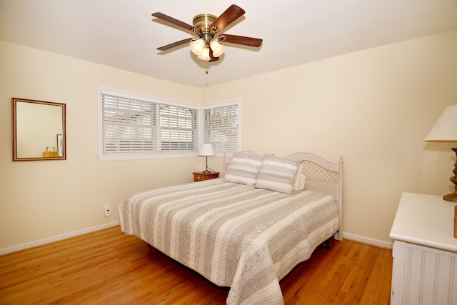 bedroom featuring baseboards, a ceiling fan, and light wood finished floors