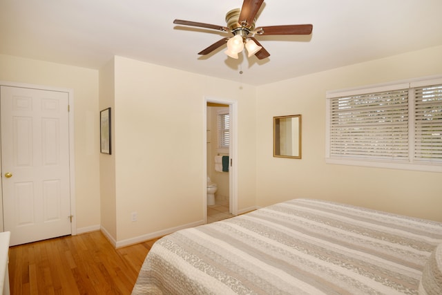 bedroom featuring ensuite bath, multiple windows, baseboards, and light wood-style floors