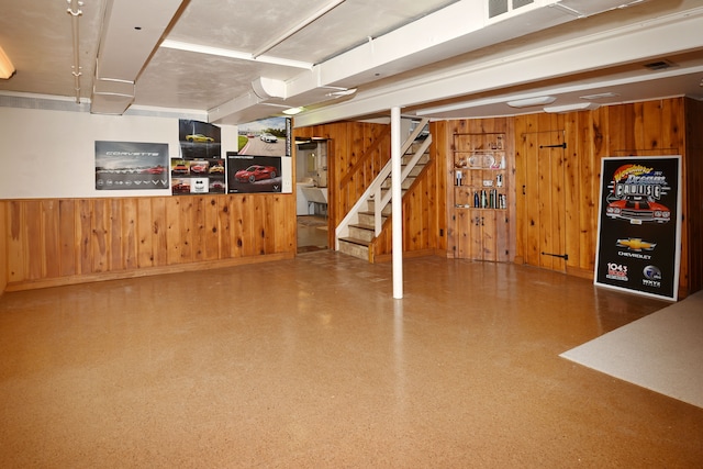 finished basement featuring stairs and wood walls