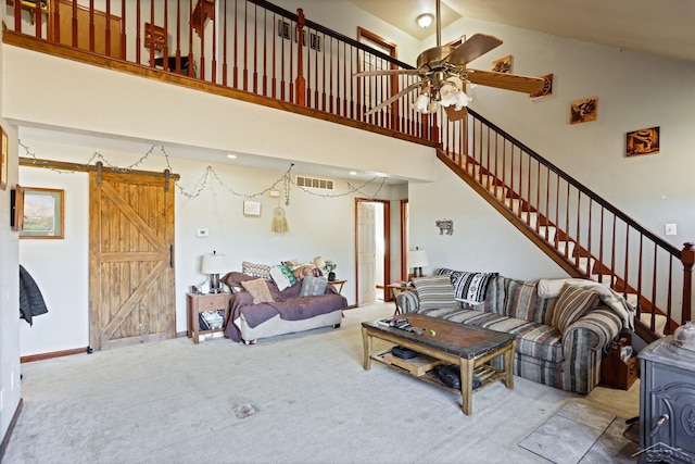 living area featuring stairs, a barn door, a towering ceiling, and carpet flooring