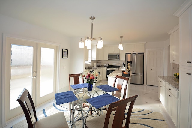 dining area with plenty of natural light, light marble finish floors, and french doors
