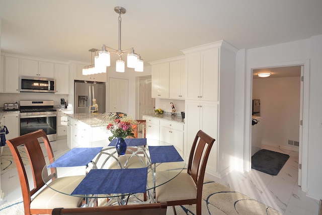 dining space featuring light marble finish flooring, baseboards, and a chandelier