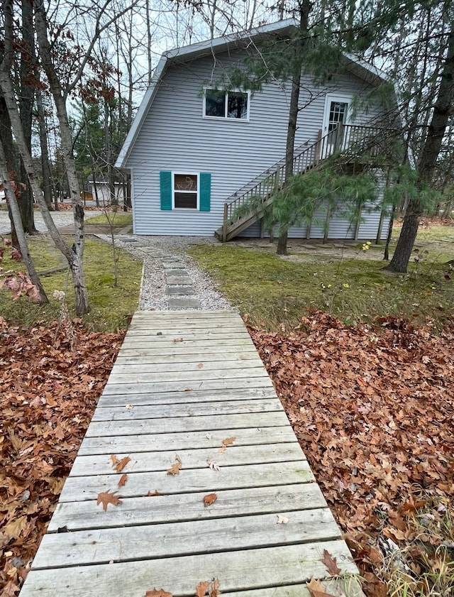 rear view of property with a gambrel roof and stairs