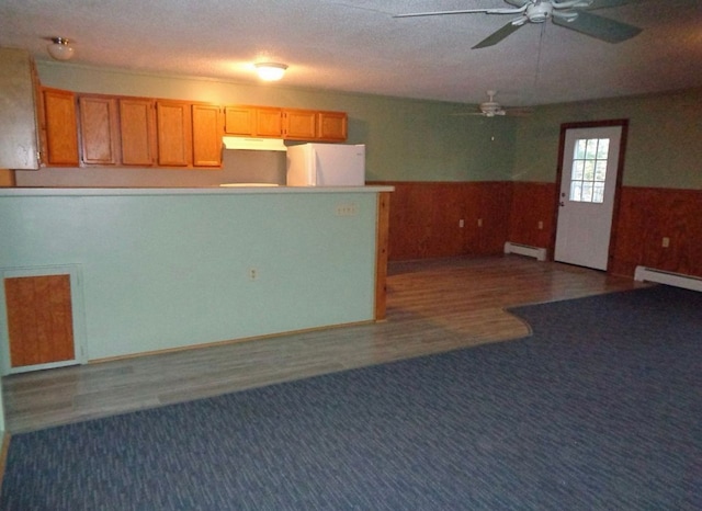 interior space featuring carpet flooring, wood walls, baseboard heating, and wainscoting