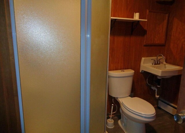 bathroom with toilet, a baseboard heating unit, and a sink