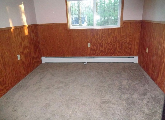 unfurnished room featuring carpet, a baseboard radiator, wood walls, and wainscoting