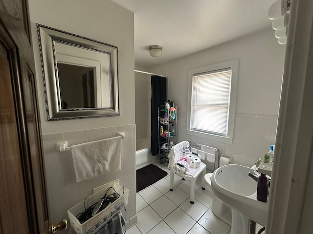 bathroom with tile patterned floors, shower / bathtub combination with curtain, a sink, tile walls, and wainscoting