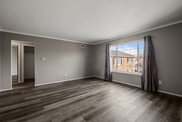 unfurnished room with visible vents, dark wood-type flooring, and ornamental molding