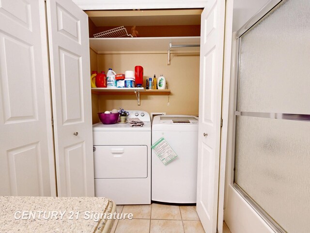 clothes washing area featuring light tile patterned flooring, laundry area, and washer and clothes dryer