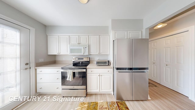 kitchen with light wood-style flooring, stainless steel appliances, white cabinets, and light countertops