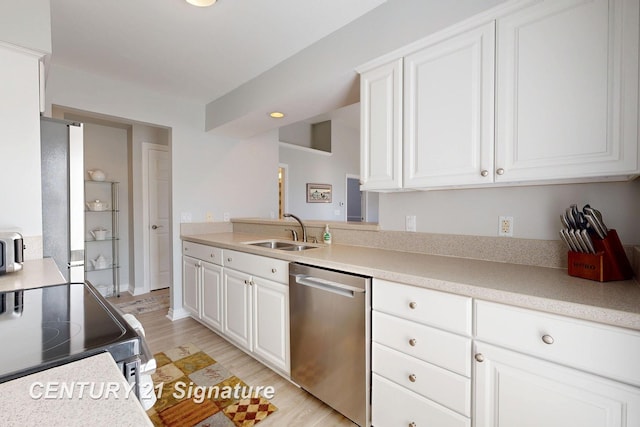 kitchen with a sink, stainless steel appliances, light wood-style floors, white cabinets, and light countertops