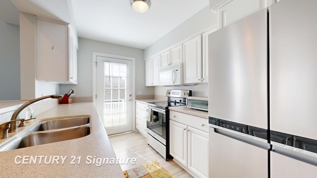 kitchen with light countertops, white cabinets, appliances with stainless steel finishes, and a sink