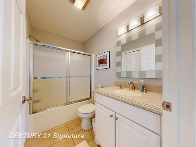 bathroom featuring combined bath / shower with glass door, toilet, vanity, and tile patterned flooring