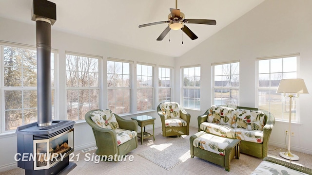 sunroom with visible vents, lofted ceiling, a ceiling fan, and a wood stove