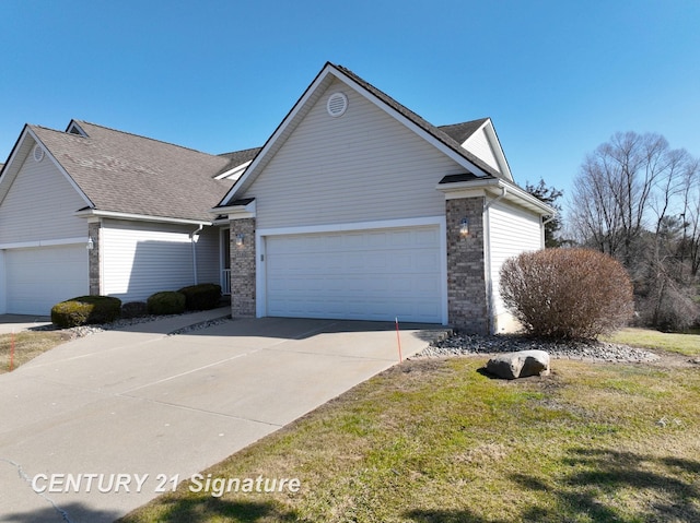 single story home with driveway, brick siding, an attached garage, and a front yard