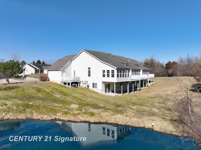 back of property with a deck with water view and a yard