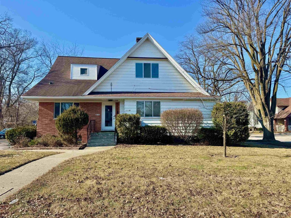 view of front facade with brick siding and a front lawn