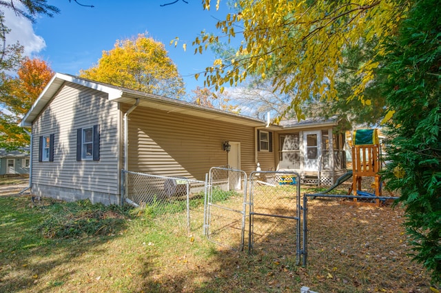 back of house with a yard, fence, a playground, and a gate