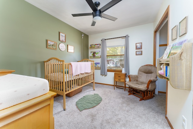 bedroom with a nursery area, baseboards, carpet, and a ceiling fan