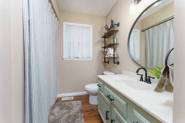 bathroom featuring visible vents, toilet, wood finished floors, baseboards, and vanity