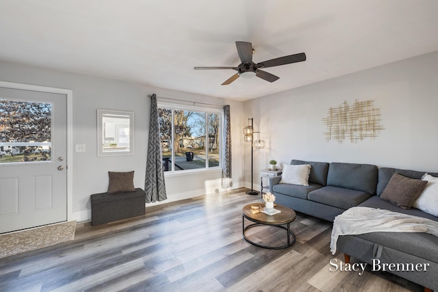 living area featuring baseboards, wood finished floors, and a ceiling fan