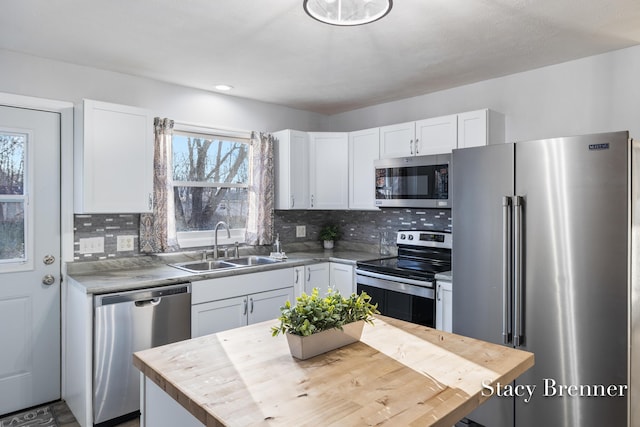 kitchen with a sink, stainless steel appliances, white cabinets, and butcher block counters