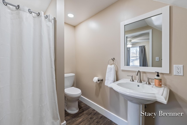 full bath with toilet, a shower with shower curtain, baseboards, and wood finished floors