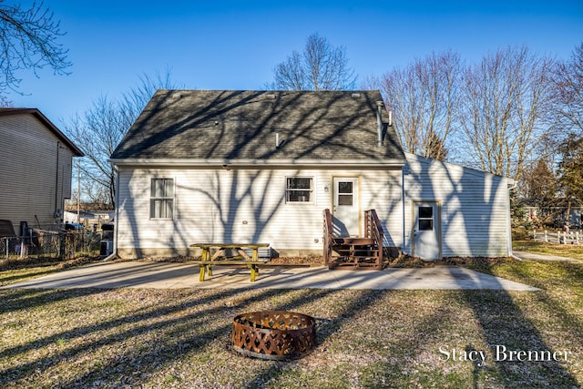 rear view of property with a patio area, a fire pit, a shingled roof, and fence