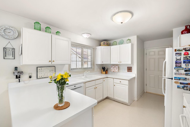 kitchen featuring white appliances, a peninsula, a sink, light countertops, and white cabinets