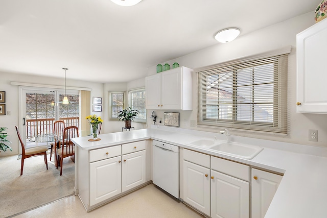 kitchen with a peninsula, a sink, light countertops, white cabinets, and dishwasher