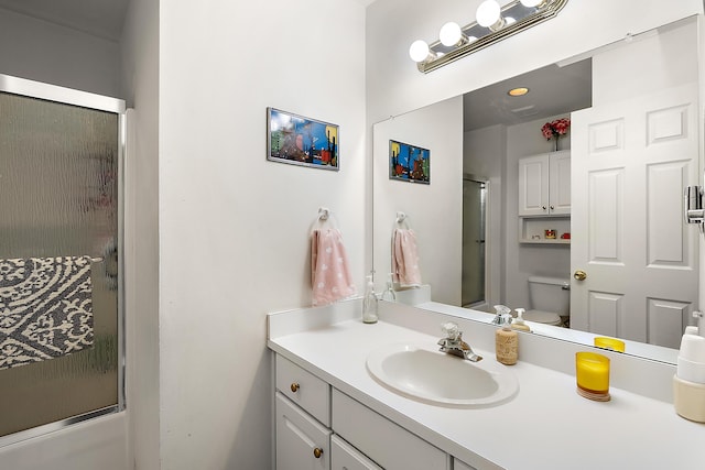 bathroom with combined bath / shower with glass door, toilet, and vanity