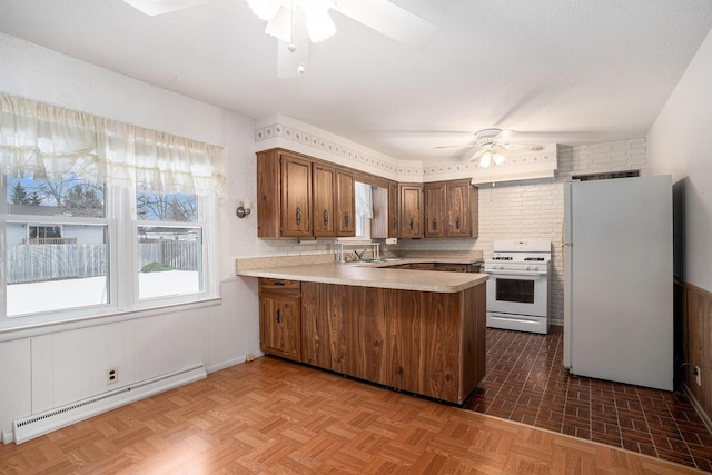 kitchen featuring white appliances, a ceiling fan, a baseboard radiator, a peninsula, and light countertops