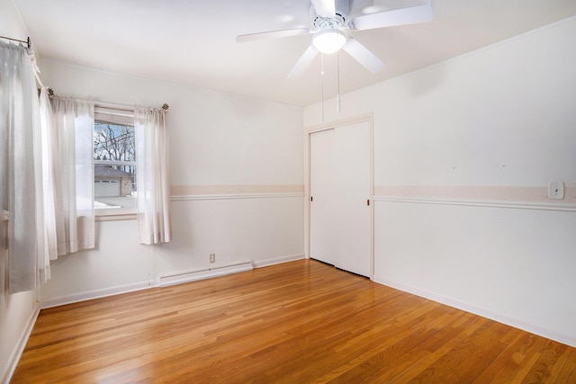 unfurnished room with a baseboard radiator, wood finished floors, and a ceiling fan