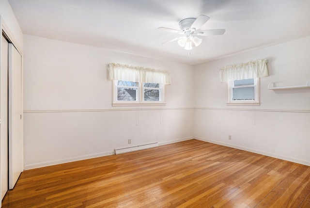 spare room featuring ceiling fan, baseboards, a baseboard heating unit, and light wood-style floors