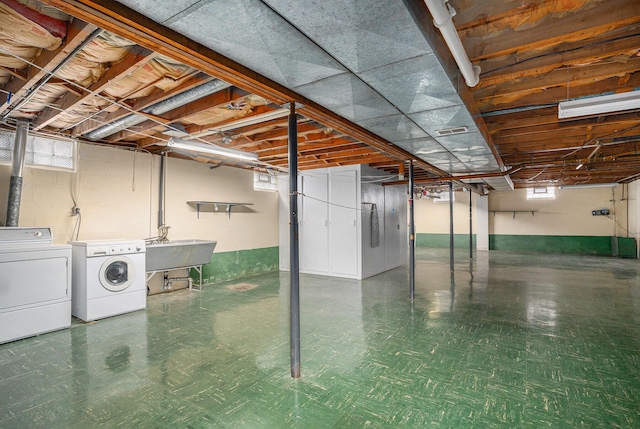 below grade area with a sink, visible vents, washing machine and dryer, and tile patterned floors