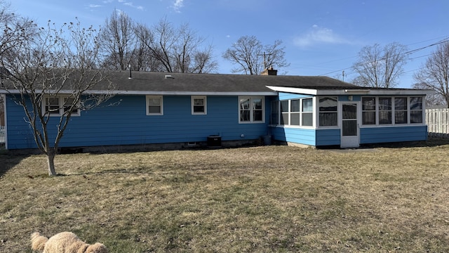 back of property featuring a lawn, a sunroom, and a chimney