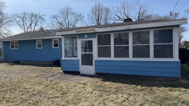 back of property featuring cooling unit, a yard, a chimney, and a sunroom