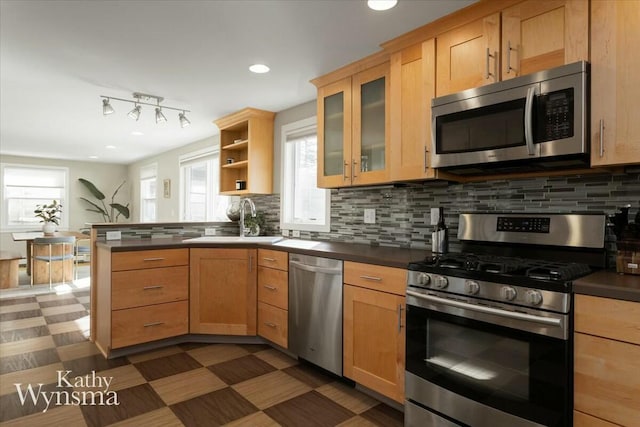 kitchen with a peninsula, open shelves, appliances with stainless steel finishes, dark countertops, and backsplash