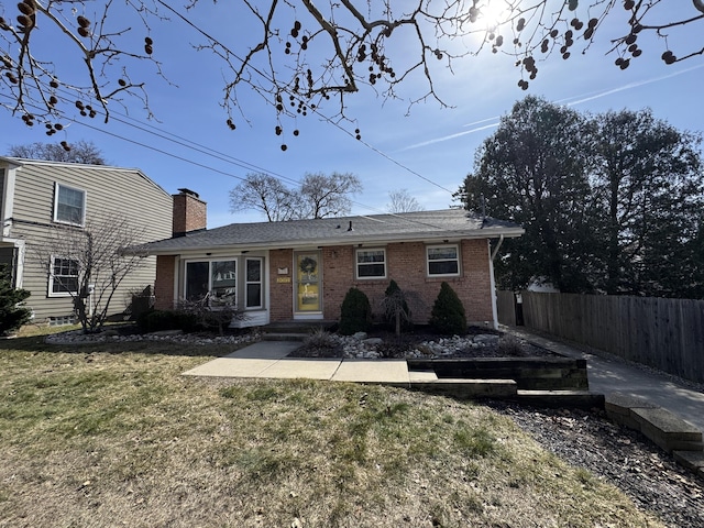 view of front of house featuring a front lawn, fence, brick siding, and a chimney