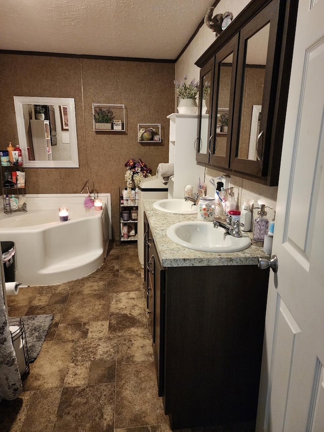 full bathroom with a sink, a garden tub, a textured ceiling, and double vanity