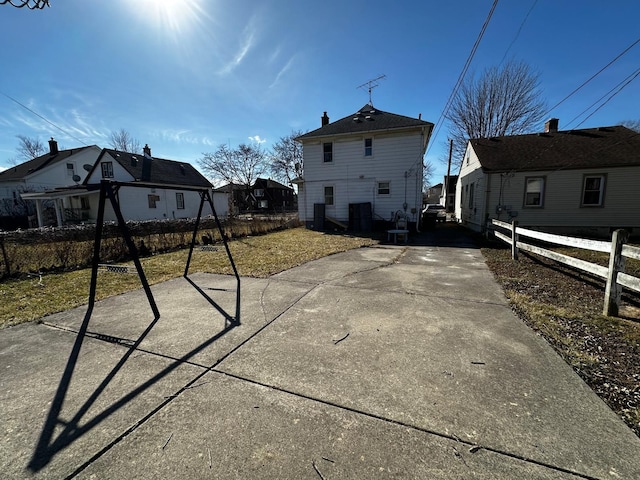 rear view of house featuring driveway and fence