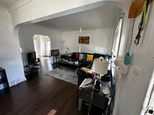 living room featuring arched walkways, wood finished floors, and ornamental molding