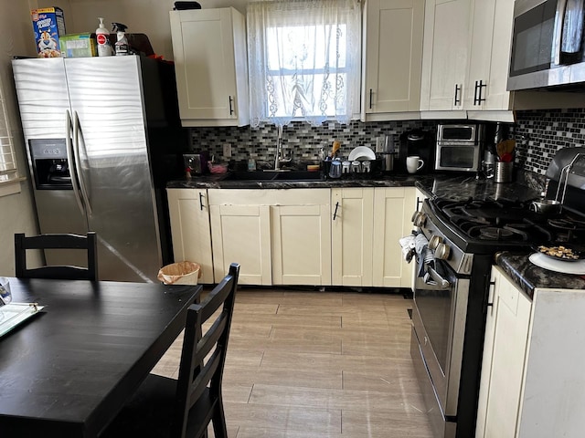 kitchen featuring dark countertops, appliances with stainless steel finishes, white cabinets, light wood finished floors, and decorative backsplash